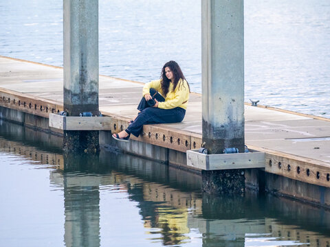 Peaceful Female Photographer Sitting on Waterfront Dock with Camera and Water Reflection at Sunrise in South Carolina