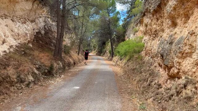 Run in sprint on footpath road in mountains. Man sprinter, runner. Male running for exercise. Greenway by bike, Bicycle. Ojos Negros Greenway is 160 km greenway in Spain. Bike track through forests an