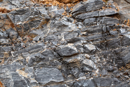 Detailed Texture of Fractured Grey Sedimentary Rock Face with Mineral Veins