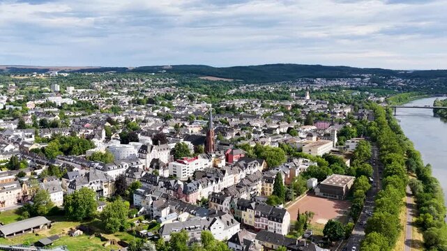 Luftbild von Trier mit der antiken R&ouml;merbr&uuml;cke &uuml;ber die Mosel, umgeben von Stadtarchitektur und gr&uuml;nen H&uuml;geln unter bew&ouml;lktem Himmel an einem Sommertag.