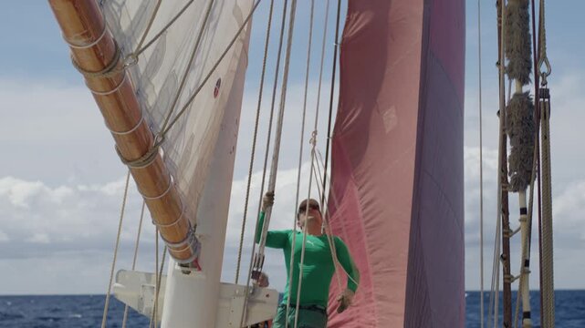 Crew work with the sails on the big expeditional sailing vessel moving in the Atlantic Ocean