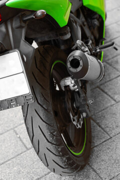 shock absorber fork and brake disc on the back wheel. exhaust pipe drive chain sport green bike parked. parking background. sports motorcycle with aluminum frame ninja