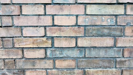Fototapeta premium Weathered old stone wall with an aged brick texture in various soft natural pastel tones, creating a rustic architectural background with copy space.