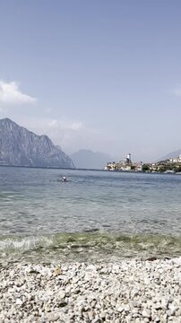 Pebble beach and Lake Garda with swimmers in Malcesine, Italy