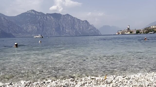 Pebble beach and Lake Garda with swimmers in Malcesine, Italy