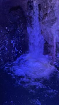 Blue illuminated waterfall flowing through rocks in Riva del Garda, Italy