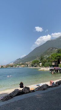 Sunny beach in Malcesine on Lake Garda, Italy, with people swimming on a summer day