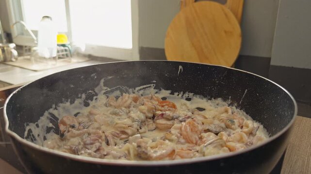 Creamy Shrimp Pasta Simmering in a Black Skillet, Warm Kitchen View Showing Homemade Seafood Dinner Preparation and Comfort Food Slow motion
