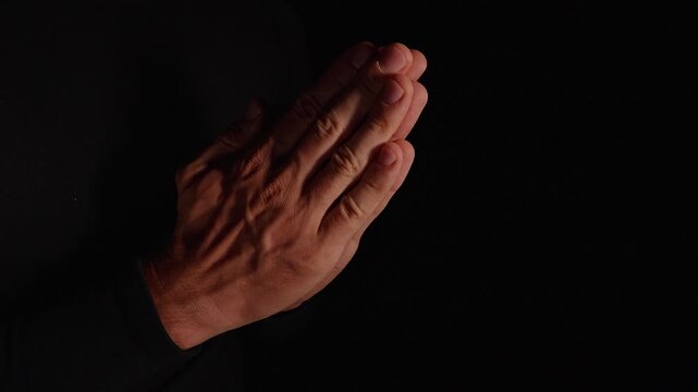 Pressed Hands Pray Against a Dark Background, Low Key Lighting Expresses Faith Reflection Hope and Spirituality