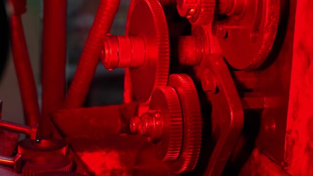 Close up of industrial machine gears and mechanical transmission system in workshop. Detailed view of rotating metal components engineering equipment and industry technology during production process