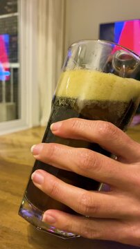 Close up of thick foam forming on top of traditional Fernet and cola alcoholic drink in a glass with ice, classic Argentine cocktail
