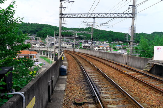 緑豊かな山を背景に大きくカーブする複線の線路と架線柱の風景