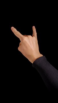 Vertical video. Hand Makes Rock Horns Gesture Against Black Background, Showing Expressive Nonverbal Communication