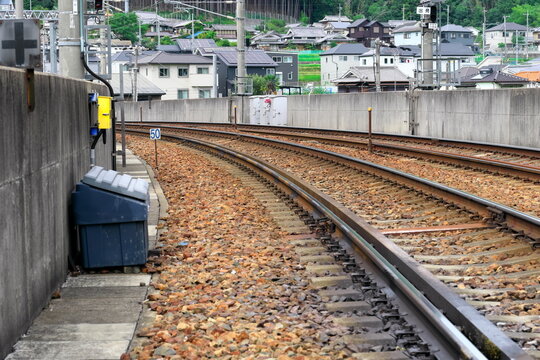 コンクリート壁沿いに続くバラスト軌道の線路とコンクリート枕木