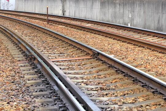 コンクリート壁沿いに続くバラスト軌道の線路とコンクリート枕木