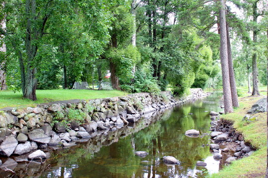 The river flows between trees with stones laid out on the banks.