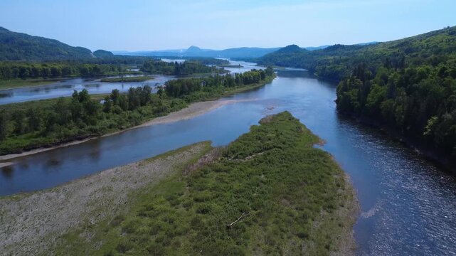 Panoramic drone footage flying over the sweeping Restigouche River valley, capturing the intricate network of green islands, sandbars, and shallow channels. The pristine landscape highlights the majes