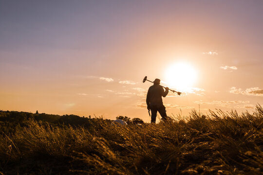 Treasure Hunter Resting His Detector Against a Glowing Evening Sky