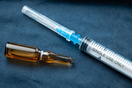 Medical syringe and ampoule placed on a dark surface
