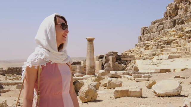 Female traveler exploring ancient Egyptian ruins near the pyramids of Giza, surrounded by historic stone structures and archaeological remains under the desert sun.