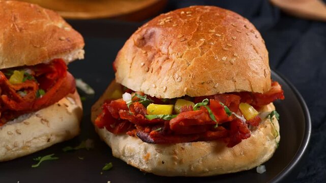 Close up of a Mexican al pastor sandwich or cemita on a dark plate