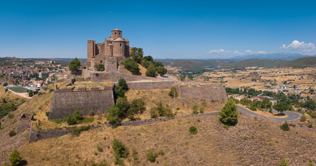 Fototapeta premium Panoramic view of medieval Cardona Castle atop a hill in Catalonia, Spain, featuring Romanesque architecture, fortified walls, and surrounding farmland stretching to distant mountains