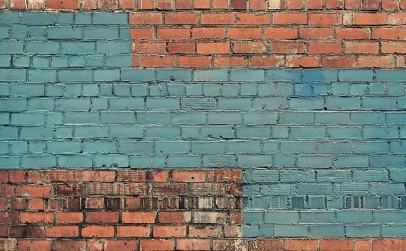 Old rustic red brick wall partially painted with light blue color blocks, abstract background texture