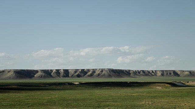 Timelaps. Expansive grassland landscape with rolling hills and clouds in the sky
