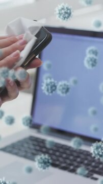 Animation of covid 19 cells over caucasian woman wiping smartphone screen