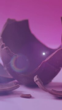 Animation of light over broken chocolate egg on pink background