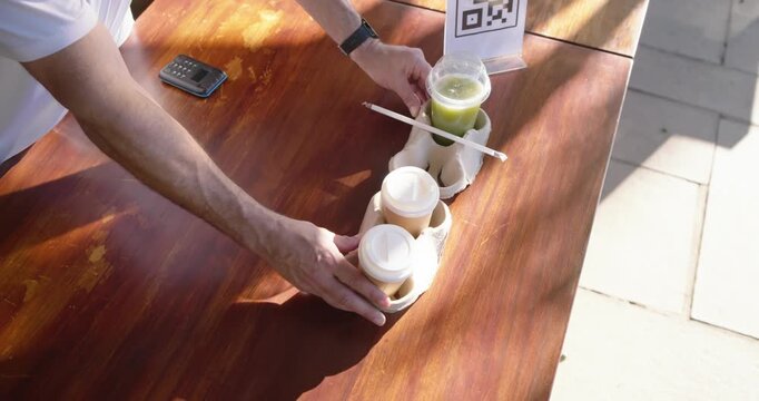 Two men scanning QR sign, showing phones, collecting drinks and coffees at pickup table, copy space