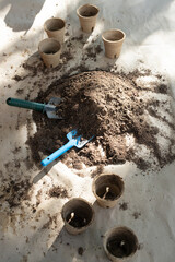 Obraz premium Potting soil mound is sitting on tarp with two trowels and peat pots under dappled sun