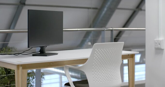 Camera is panning, revealing white office chair with black cushion, desk and monitor, showing loft