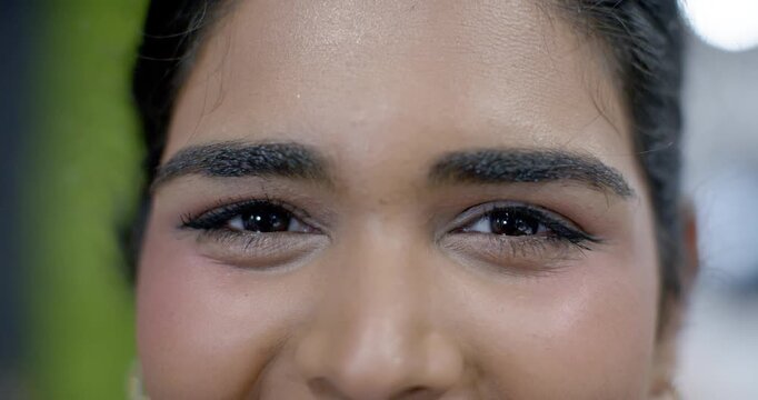 Indian woman holding camera eye contact, blinking from studio light while posing showing eye makeup