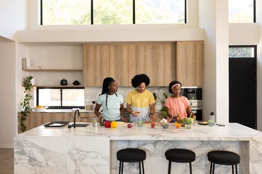 African American family preparing meal at marble kitchen island chopping veggies with chef's knife