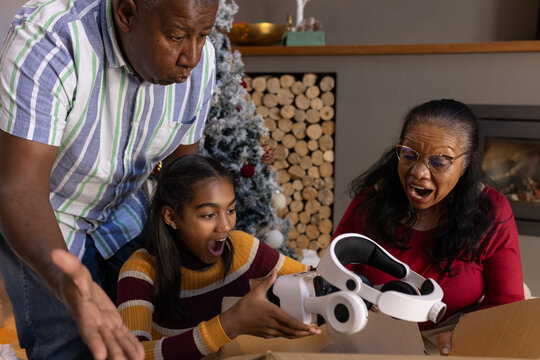 African American family reacting with surprise while unboxing white VR headset at cozy living room