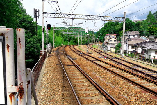 緑豊かな山を背景に大きくカーブする複線の線路と架線柱の風景