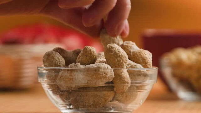 Peanuts in Salted Shell Man Cracking and Eating Salty Nuts as a Classic Bar Snack at Cafe