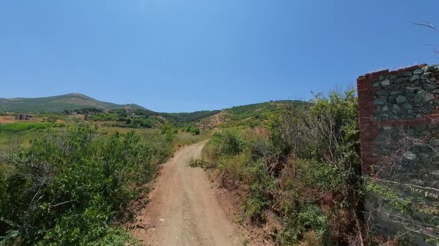 Flying close on a countryside road near the mountain with a beautiful pond near the end of the trail