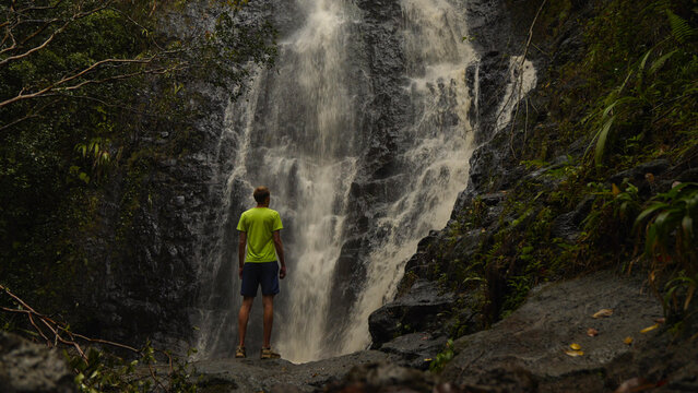 Person standing in front of a large waterfall in the Hawaiian jungle