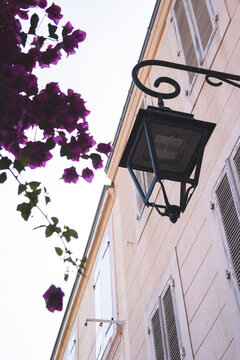 Marseille, France - 1 August 2026 : Le Panier neighborhood, classic black wall-mounted street lantern with an LED fixture attached to a pale peach-colored Mediterranean building facade adorned with vi