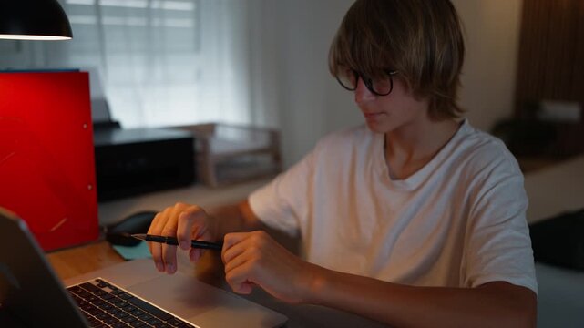 Teen student wearing glasses and using a computer for schoolwork at home. Screen time, digital wellbeing, healthy technology use, online education and balanced student lifestyle concept.