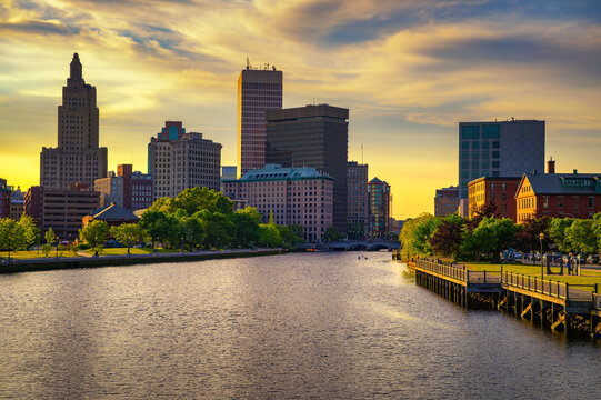Golden sunset lights downtown Providence and the Providence River in Rhode Island, USA, with historic towers, waterfront walkways, and a calm urban skyline.