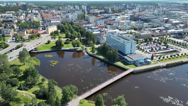 Oulu, North Ostrobothnia, Finland - 04 August 2026: Aerial view of Oulu city center with the Oulujoki river, lush green parks, and modern buildings under a clear summer sky.