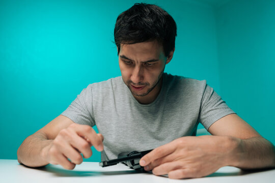 Young man receiving new gadget and focusing on setting it up, studying and preparing device for use, demonstrating attention to detail and engaging with modern technology.