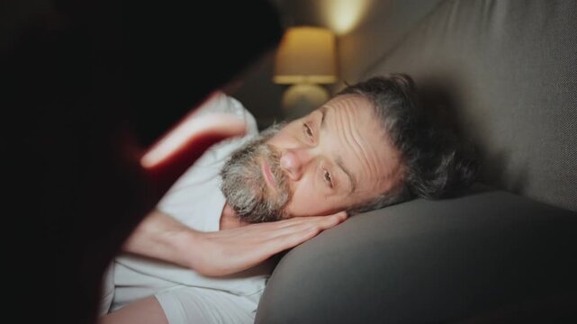 A man lying in bed using smartphone late at night