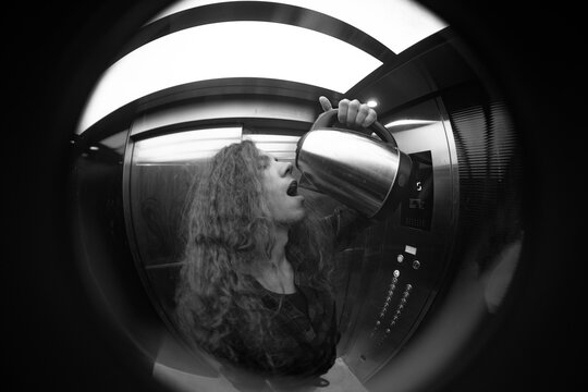 Monochromatic concept of exhausted man with electric kettle in elevator with copy space