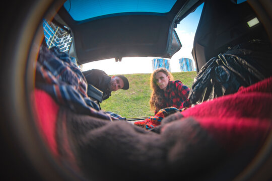 Friends looking inside car trunk during road trip adventure with copy space