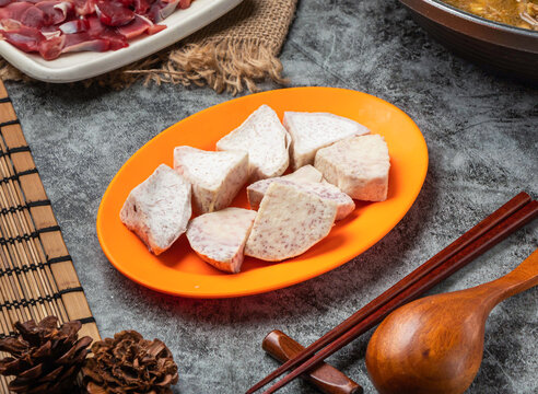 Fresh raw taro root chunks on an orange plate for hot pot cooking