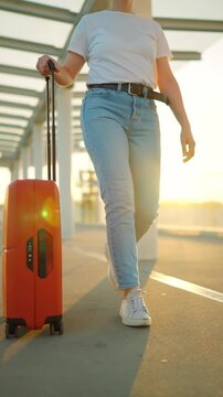 Woman confidently pulling a suitcase in an airport terminal. Slow motion.